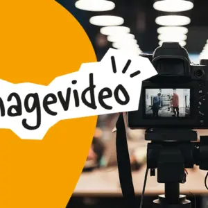 Digitalkamera auf einem Stativ filmt zwei Personen in einem hellen Raum mit vielen Deckenleuchten, davor orangefarbener Bereich mit Schriftzug Imagevideo.