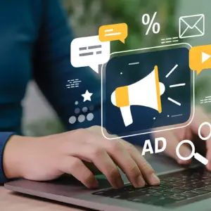 Person tippt auf Laptop-Tastatur, darüber Symbole für Werbung, Nachrichten, Suche und Social Media erscheinen digital.